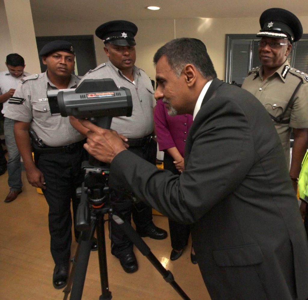 Works and Transport Minister Rohan Sinanan looks through the view-finder of one of the nine recently acquired LIDAR speed guns as they were handed over to the Police Service on November 23.