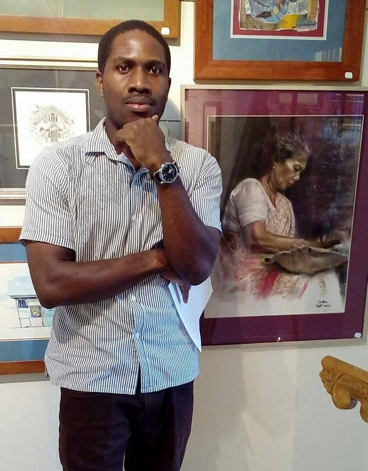 Artist and entrepreneur Jadon Matthews poses with a few of his pieces on display at the Upper Level Art gallery in Mt St Benedict. Photo by Shane Superville