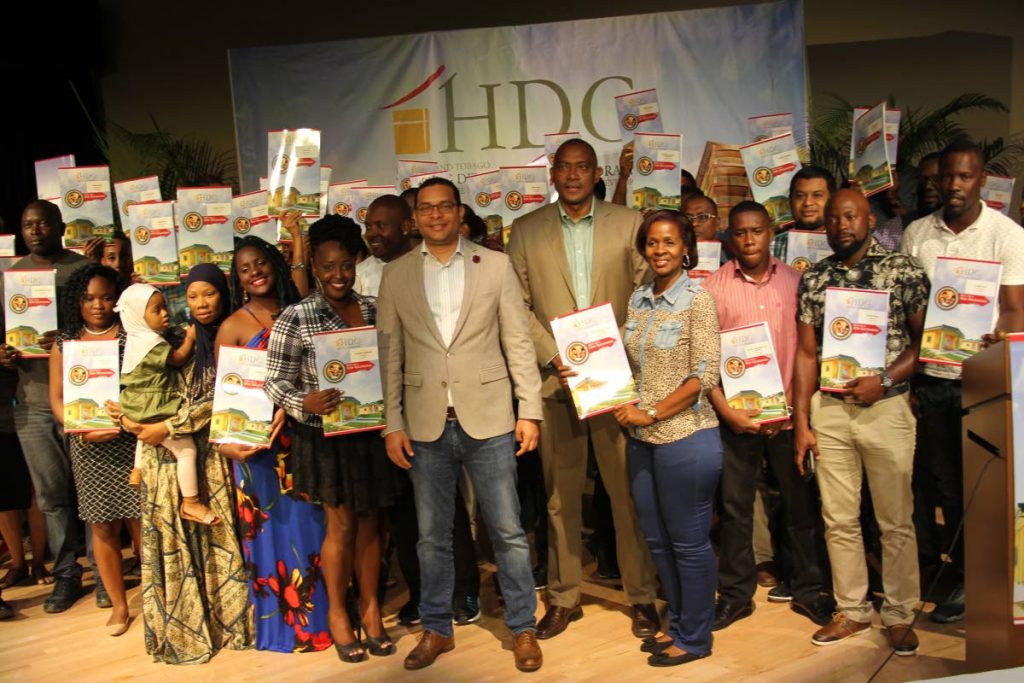Minister of Housing Randall Mitchell, centre left, and Brent Lyons, managing director of the Housing Development Corporation, centre right, pose with families that received their packages at a housing allocation ceremony at Government Campus Plaza, Port of Spain, yesterday. PHOTO BY RATTAN JADOO