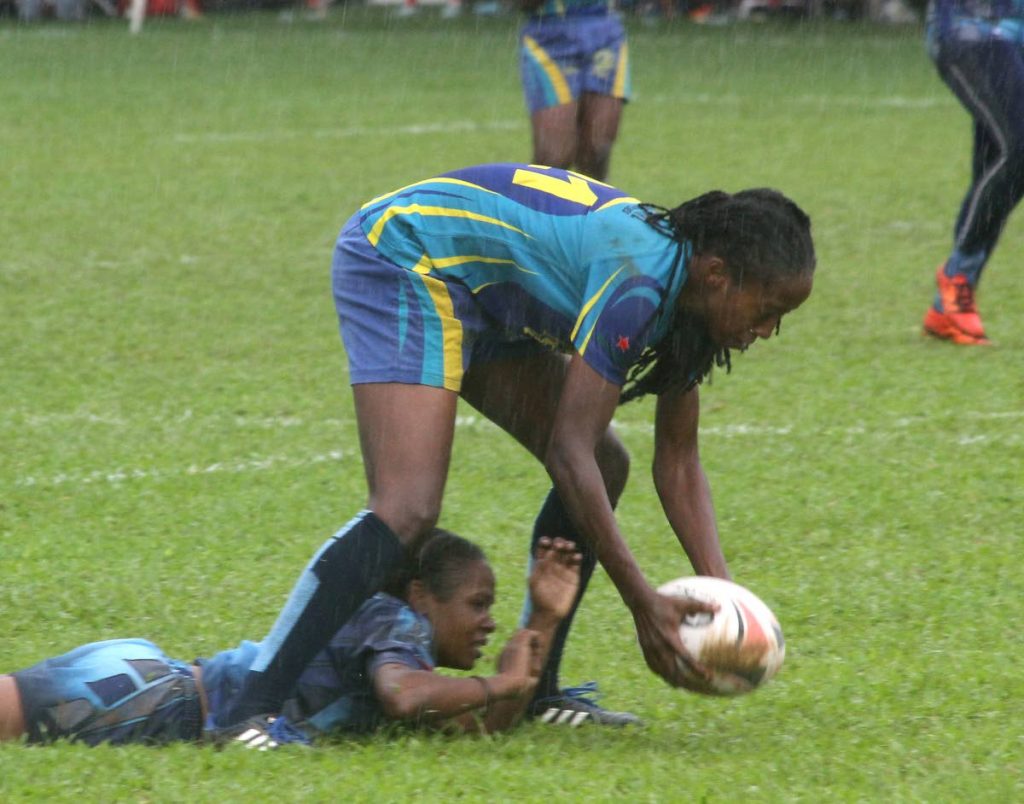A Royalians player picks up the ball after her Police rival falls in a women’s clash at the Harvard Heineken Rugby Festival yesterday at St Mary’s Ground, St Clair. Royalians won 17-12.
