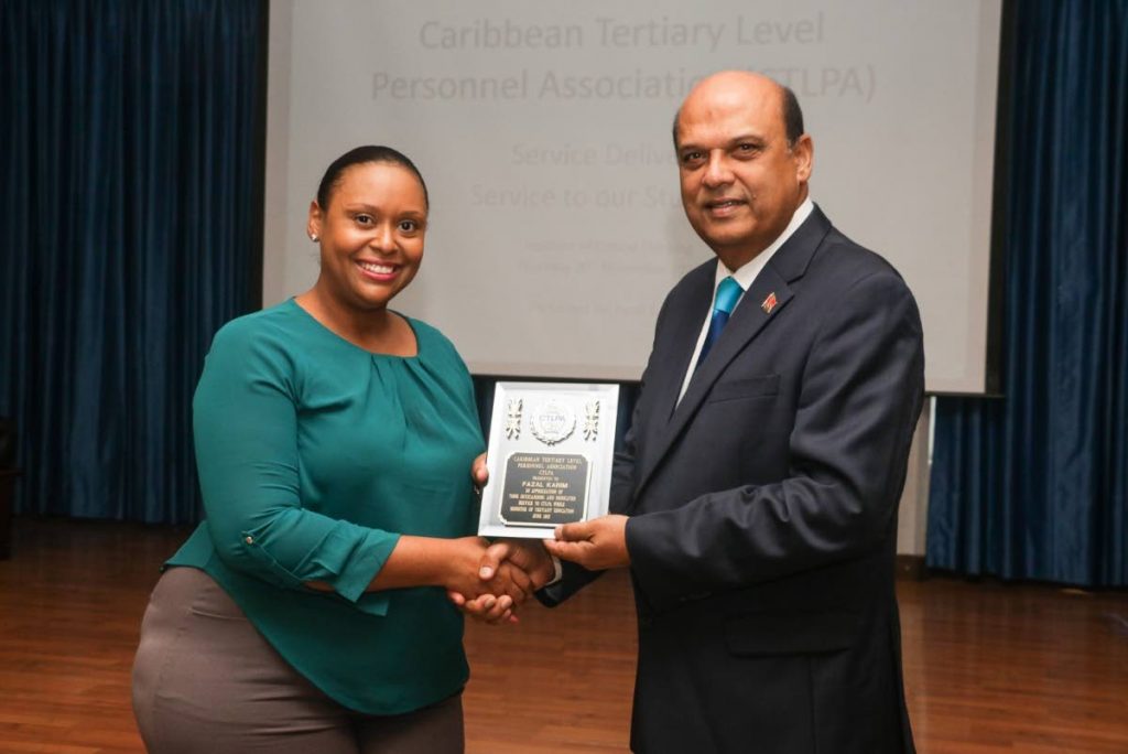 HONOURED: Former Tertiary Education and Skills Training Minister Fazal Karim receives an award from Roxanne Bartholomew, president of the Caribbean Tertiary Level Personnel Association last week. 