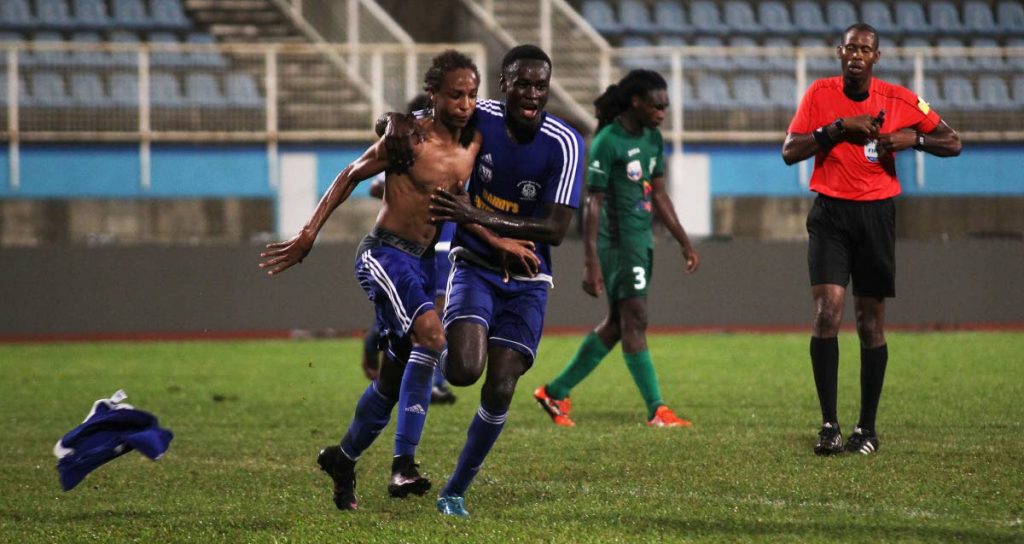 Shiva Boys’ Tyrel Emmanuel, left, takes off his shirt to celebrate his and his team’s second goal against San Juan North on Monday in the Coca Cola Intercol final at the Ato Boldon Stadium, Couva.
