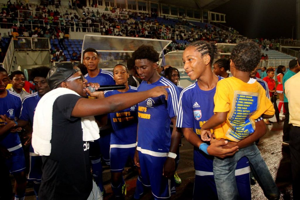 Soca Monarch champion Aaron ‘Voice’ St Louis, left, sings to newly crowned Coca Cola Intercol champs Shiva Boys after their 2-0 win over San Juan North in the final on Monday at the Ato Boldon Stadium, Couva.