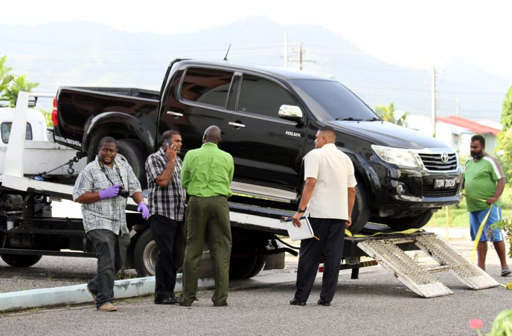 EVIDENCE: Police near a heavily tinted pick-up van which they believe was used in a daring $5 million hold-up by bandits at Piarco International
Airport. PHOTO BY SUREASH CHOLAI