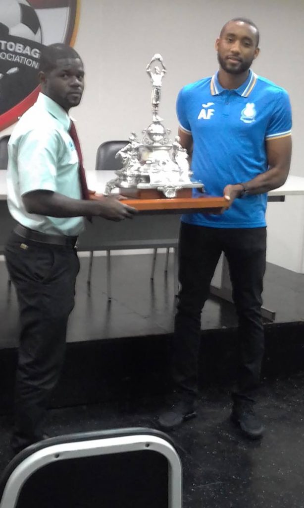 W Connection captain Hughtun Hector (left) and Police FC goalkeeper Adrian Foncette pose with the TTFA FA Trophy in a media conference at the Ato Boldon Stadium, Couva yesterday.