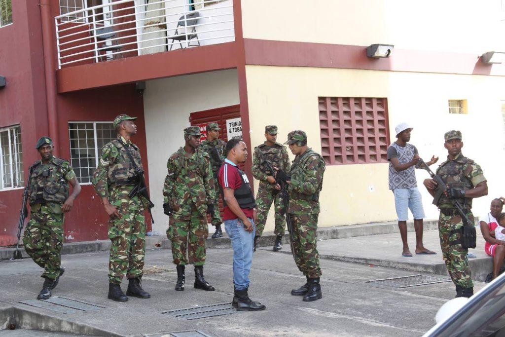 Army and police officers keep watch in front of the Cliffton Hill towers on St Paul Street in Port of Spain yesterday.