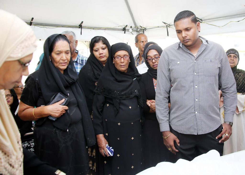 GRIEF: Tamina Mohammed (second from left) views the body of her murdered daughter Alicia Mohammed at the funeral held at John Peter Road, Charlieville yesterday.  She is supported by her son PC Anwar Mohammed (right) and other relatives.
