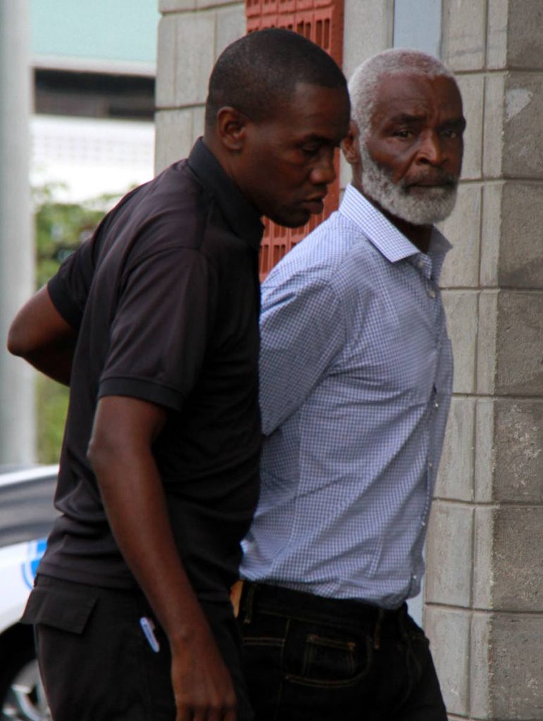 OFF TO COURT: 64-year-old Claude Mike (right) is escorted into the Princes Town Magistrates Court yesterday charged with shooting two-year-old Candy Loubon at Moruga.    PHOTO BY ANIL RAMPERSAD