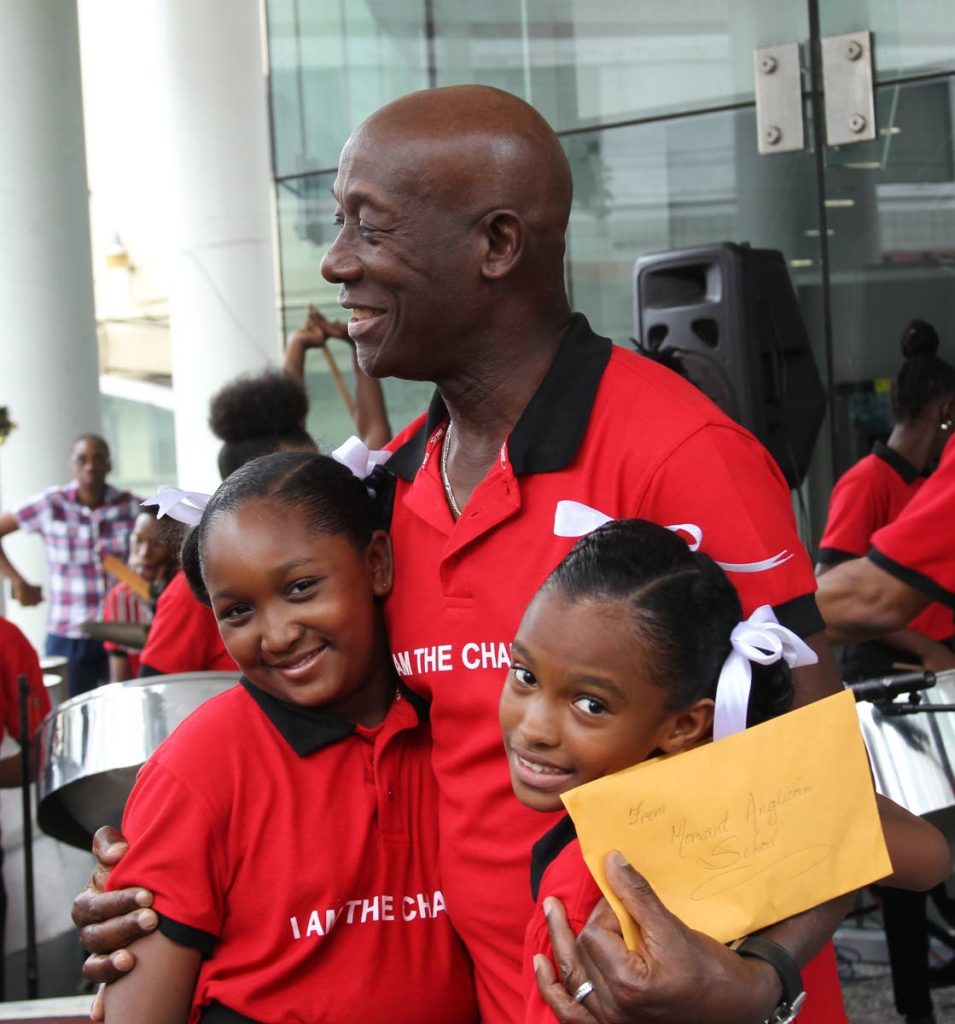 HUGS FROM PM: Prime Minister Dr Keith Rowley hugs Morvant Anglican Primary School students Tfarah Homer and Tyra Lyons after they presented to him money raised by the school for children in Dominica which was devastated by Hurricane Irma.  Rowley was at the Ministry of Education where children sang Christmas carols.