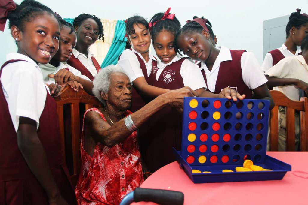 YESTERDAY’S CHILDREN: Jocelyn Leech, a resident at the Helena Charles Home for Senior Citizens, plays a game with students of the La Brea RC Primary School yesterday.  PHOTO BY LINCOLN HOLDER