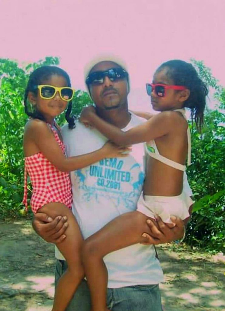 HAPPIER TIMES: Policeman Richard Babwah, who was shot dead during a robbery attempt in Arouca on Monday, with his daughters Raianne, left, and Renisha, both nine, during a recent beach lime.