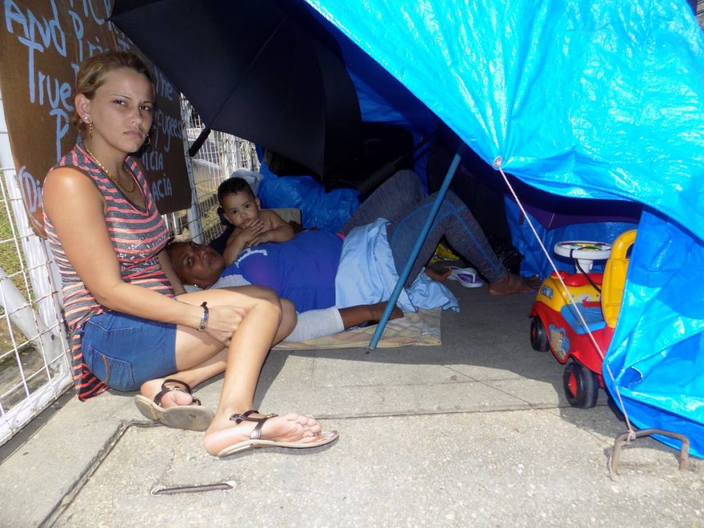 Cuban asylum-seekers Lisa Perez, her mother Sandra Rodriguez and infant son Liusnel Perez take shelter from the sun using a tarpaulin, tied to the gate of the United Nations building, Chancery Lane, Port-of-Spain.  
Perez says they have been using washrooms at the Queen's Park Savanna to shower. 