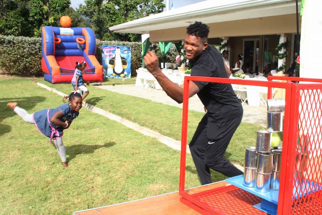 Olympian Keshorn Walcott, right, has fun with this girl at a Christmas party hosted recently alongside bmobile at his home in Valsayn.