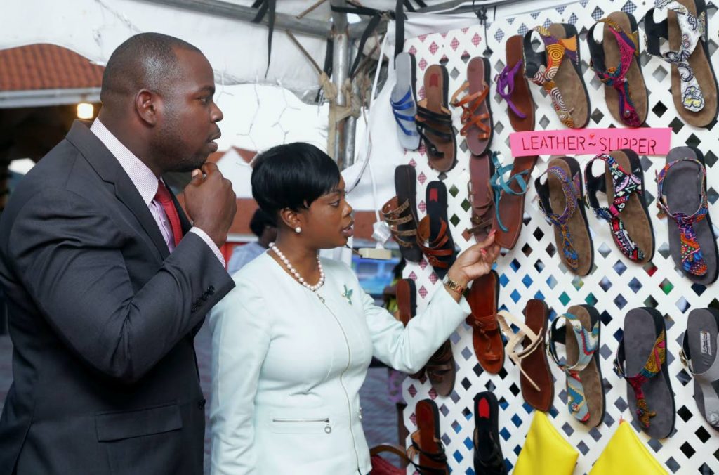 Tourism Secretary Nadine Stewart-Phillips, right, and Assistant Secretary of Community Development Shomari Hector, look at hand-crafted sandals on display at a booth at the Christmas Village on the Milford Road Esplanade last week.