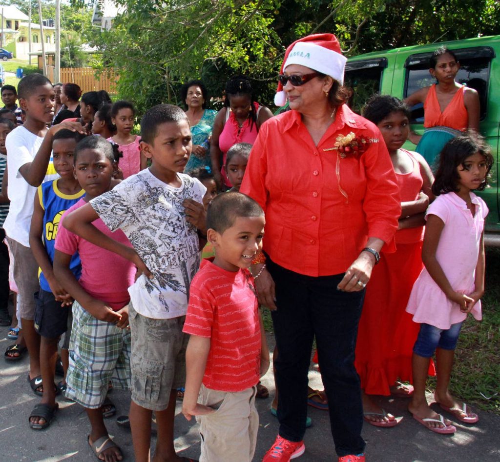SANTA KAMLA: Opposition Leader Kamla Persad-Bissessar with children during her annual Christmas toy drive on Monday at Rock Road in Penal.