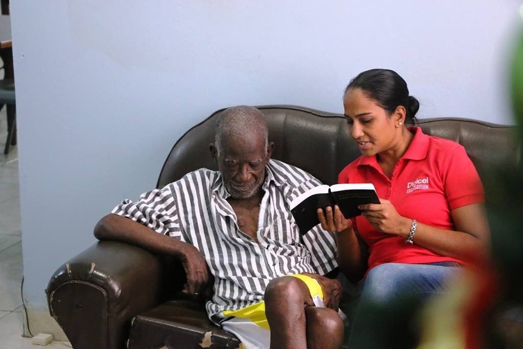 Digicel Foundation project coordinator, Diana Mathura-Hobson, right, reads a Psalm to this man.