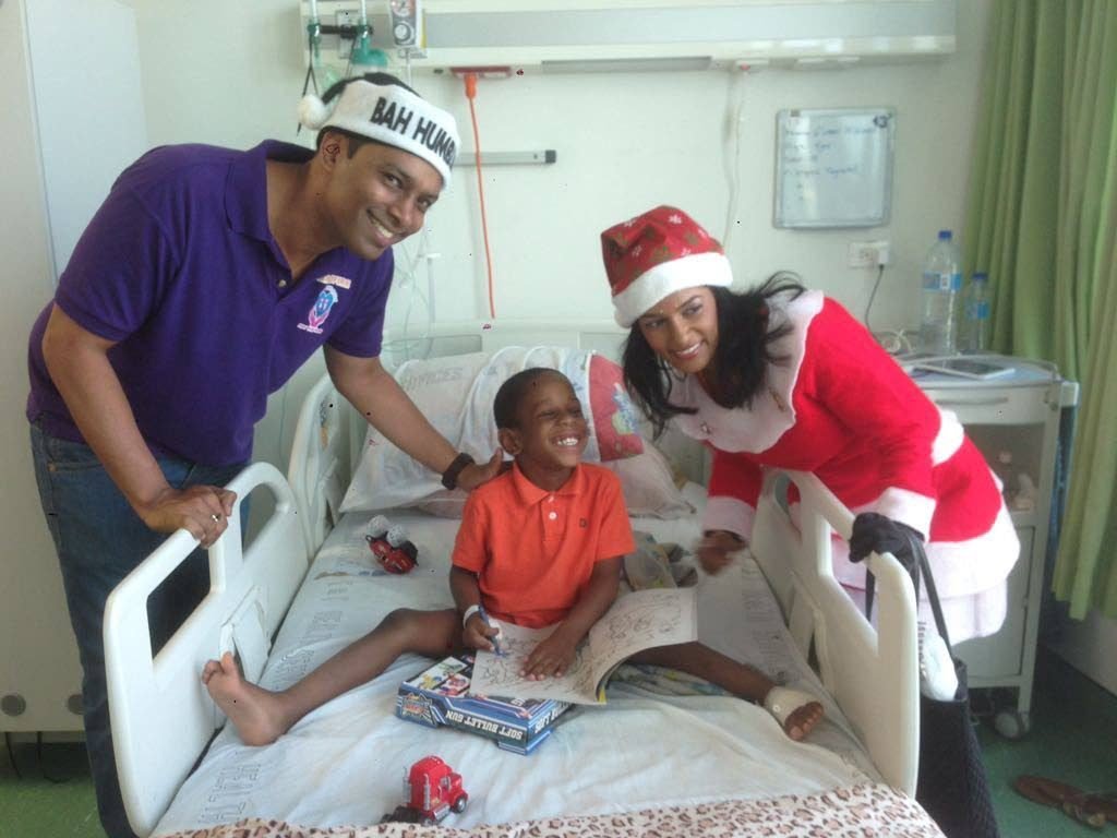 BRINGING CHEER: Rapid Fire Kids executive member Kevin Ratiram and friend of the group Khyma Lutchman brings joy to a child at the teaching hospital in San Fernando.