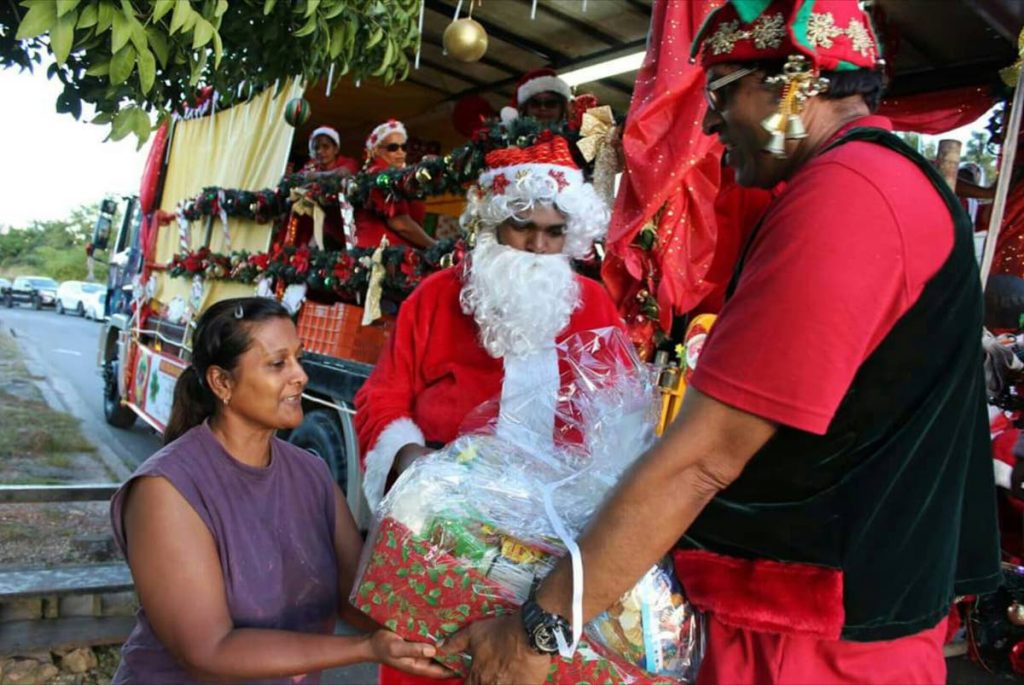 FOR YOU: Alexis Sieunarine, dressed as Santa Claus, looks on as a helper gives a woman a Christmas hamper. Sieunarine and his father businessman Allan Sieunarine were behind an initiative which saw over 4,000 hampers being given to needy children during the Christmas Season.