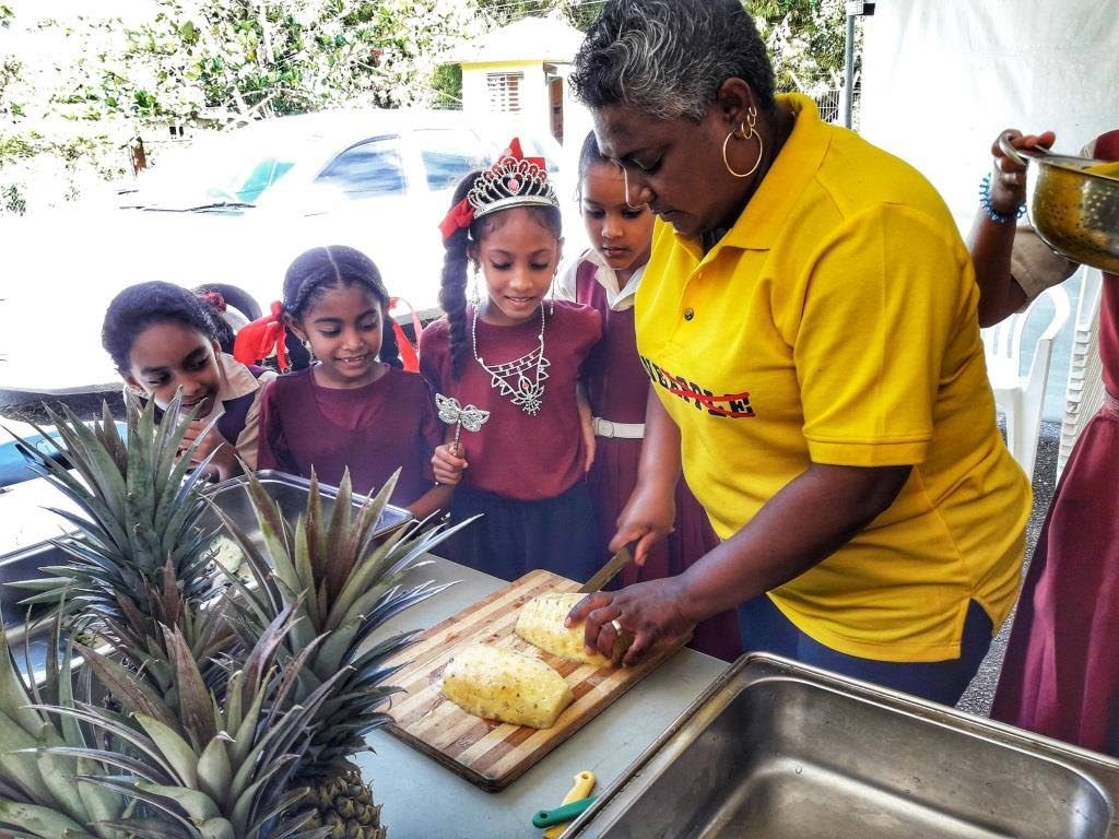 Children anxiously await their share of fresh pineapple at Eat Local Day on December 13, held at the Sisters Road Anglican School.