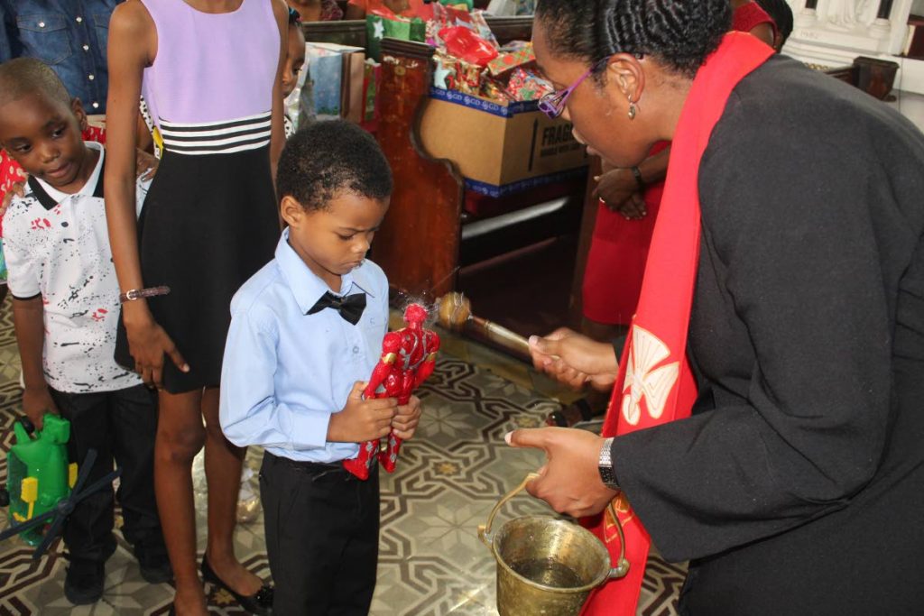 Reverend Shelley Tenia blesses children and their toys at the Feast of the Holy Innocents service Holy Trinity Cathedral, Port of Spain. PHOTO BY ENRIQUE ASSOON