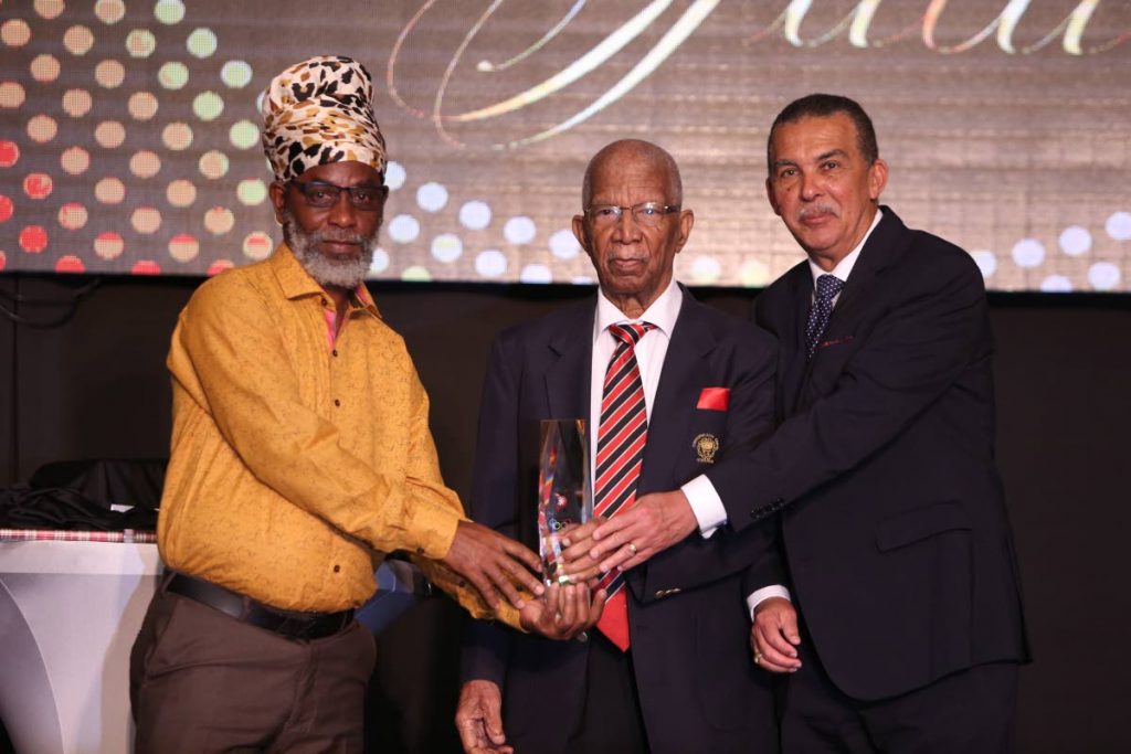 Anthony ‘Dada’ Wickham, left, coach of Trendsetter Hawks, collects the prestigious Alexander B Chapman Award from President Anthony Carmona, right, and Chapman, centre, at the TTOC Awards on Friday at the Hyatt Regency, Port of Spain.