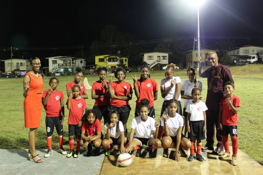 Nicole Olivierre, left, MP for Point Fortin, and Public Utilities Minister Robert Le Hunte, back right, pose with footballers at the illumination ceremony of the Bennett Village Recreation Grounds, recently.