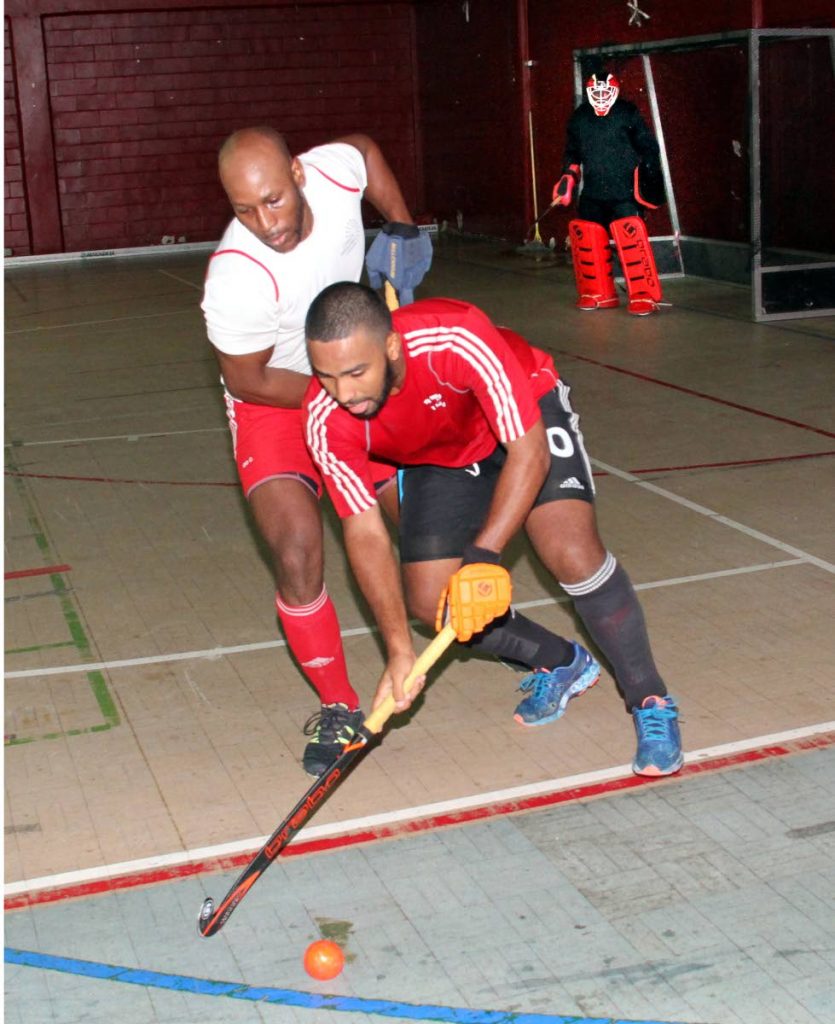 TT national hockey player Jordan Reynos goes around President 11 player Terrance Baptiste in a practice match at the Woodbrook Youth Facility last month.