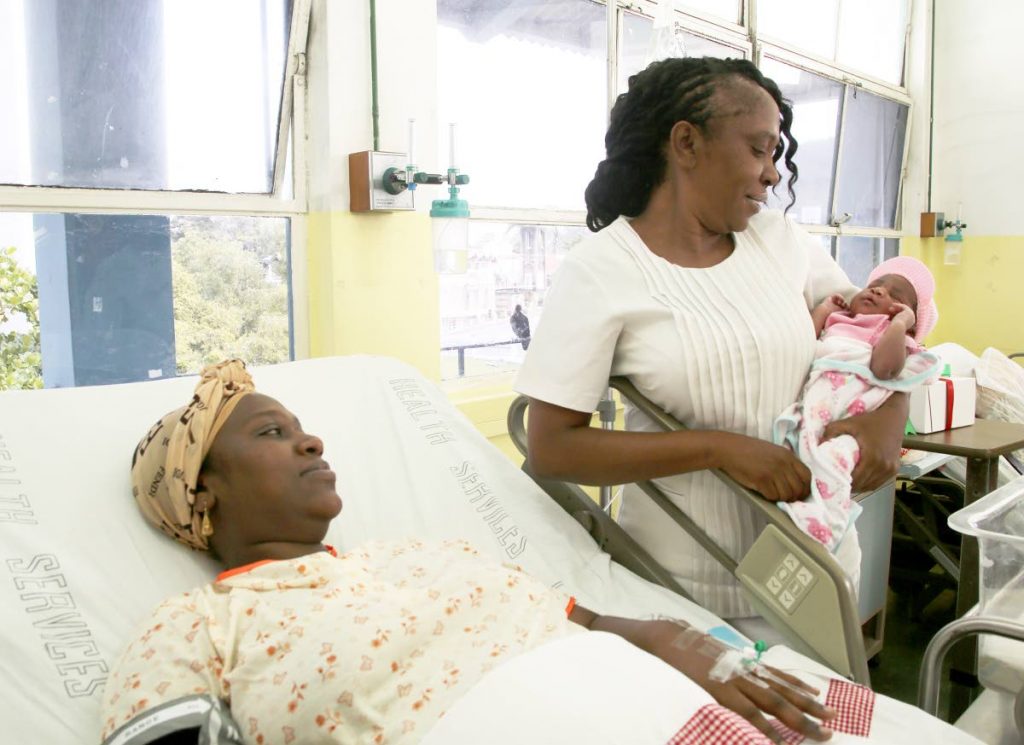 PRETTY IN PINK: Baby Pniya Fletcher is the centre of attention as she is held by nurse Cherry King while her mother Kerisha Pierre looks on at the San Fernando General Hospital yesterday.