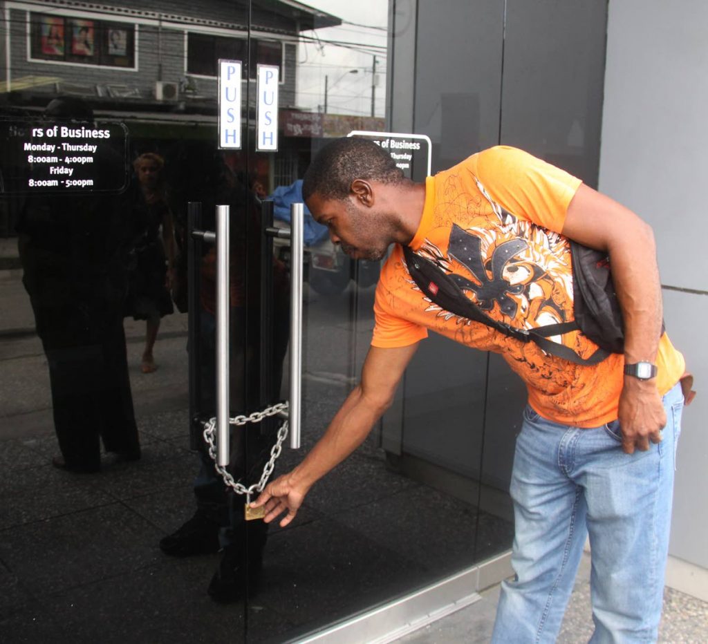 CLOSED: An RBC Sangre Grande customer checks the lock on the door of the branch.