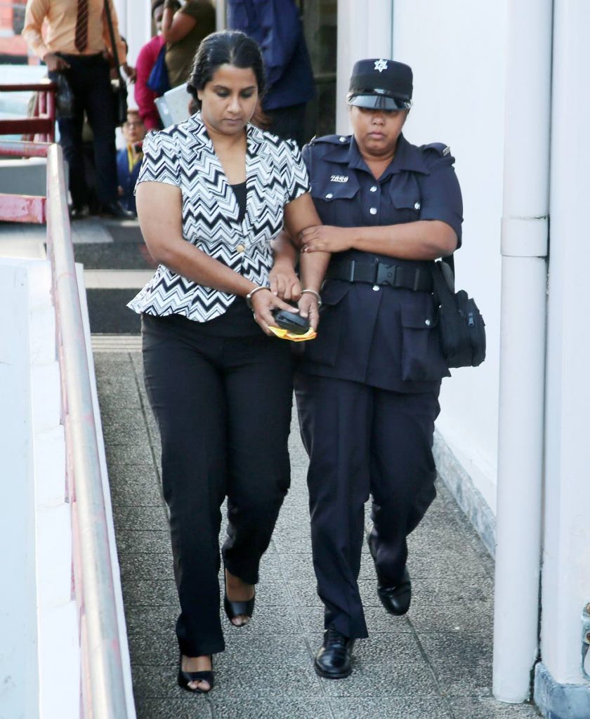 Vicky Boodram is escorted out of the San Fernando magistrates court after appearing on over 109 fraud charges yesterday.   PHOTO BY VASHTI SINGH