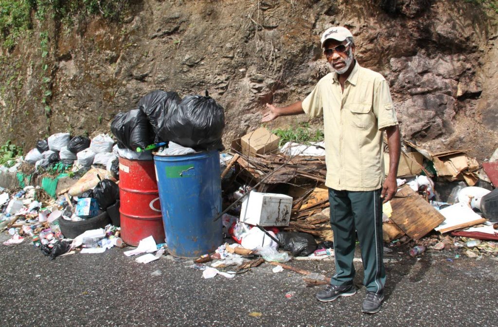 STINK SITUATION: Roland Augustus points to piles of garbage dumped along Morne Coco Road. PHOTO BY SUREASH CHOLAI