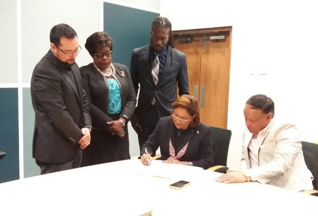 SIGNED: Opposition Leader Kamla Persad-Bissessar signs the document confirming the Opposition’s support of Government’s nominee for President, retired judge Paula Mae Weekes. Looking on from left are Govt MPs Stuart Young, Camille Robinson Regis and Adrian Leonce while seated at right is Opposition MP David Lee.