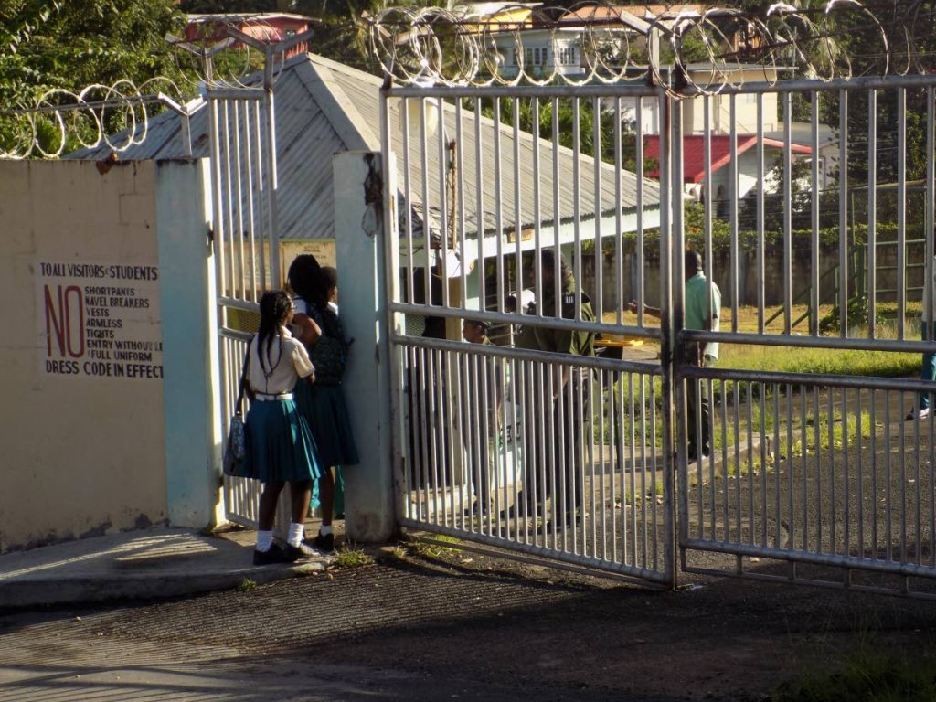 Students of the Morvant Laventille Secondary School arrive with their parents for class yesterday after form two student Joshua Andrews was killed in a taxi in Pelican Extension, Trou Macaque on Monday.