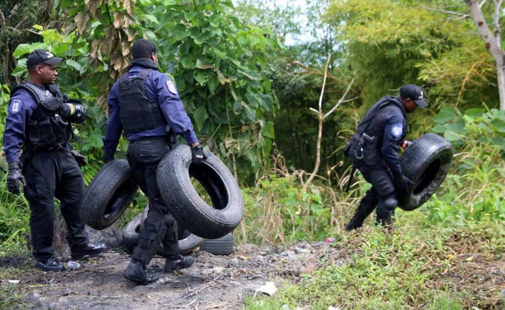 TOTING TYRES: Police throw tyres into the bushes shortly after clearing a road in 6th Company, New Grant, as residents protested for a third straight day yesterday over the dilapidated condition of the road. PHOTO BY VASHTI SINGH
