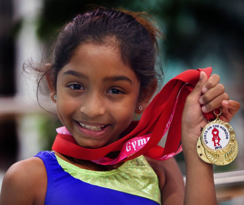 Hailey Ali shows off medals she won for hula hoop events, gymnastics and Scrabble.