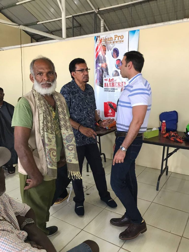 PROACTIVE: Homeless Frank Deonarine, left, 
at the San Fernando Centre for Displaced 
Persons. At centre is Minister of Rural and 
Local Government Kazim Hosein.