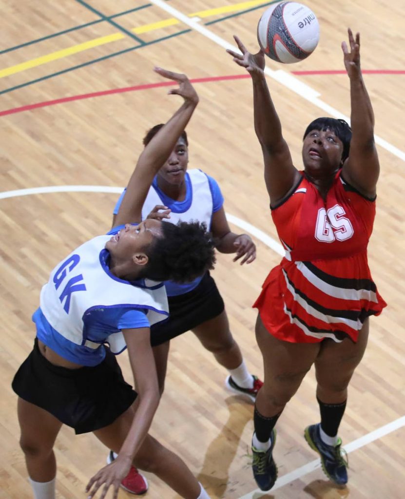 UTT’s Anastascia Wilson, right, receives a pass over the head of UTT’s Sanya Jarvis, left, in a Courts All Sectors Netball League game at the Maloney Indoor Sporting Arena, Saturday.