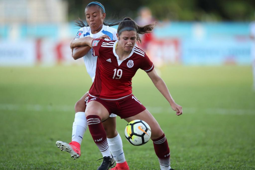 Mexican striker Venica Juarez Smith,foreground, is challenged for the ball by a Nicaraguan defender yesterday in their Group B match at the Ato Boldon Stadium, Couva for the CONCACAF U20 Women’s Championships.