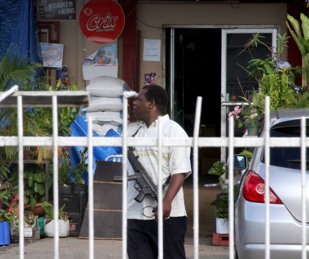 ON GUARD: A policeman is seen at  Wong’s Supermarket in Diego Martin yesterday after proprietor Franklyn Wong was shot dead during a hold-up. PHOTO BY ROGER JACOB