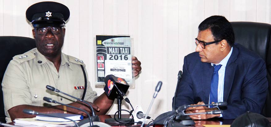 Ag Supt Edwin Phillips of the Transit Police Branch displays a fraudulent PBR maxi-taxi pass during a press conference hosted by Works and Transport Minister Rohan Sinanan, right, yesterday.