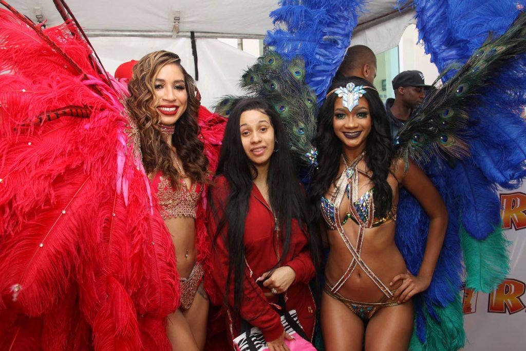 I’M HERE: American rapper, singer and songwriter Cardi B pose with two masqueraders on her arrival at the Piarco International Airport yesterday.   PHOTO BY ANGELO MARCELLE