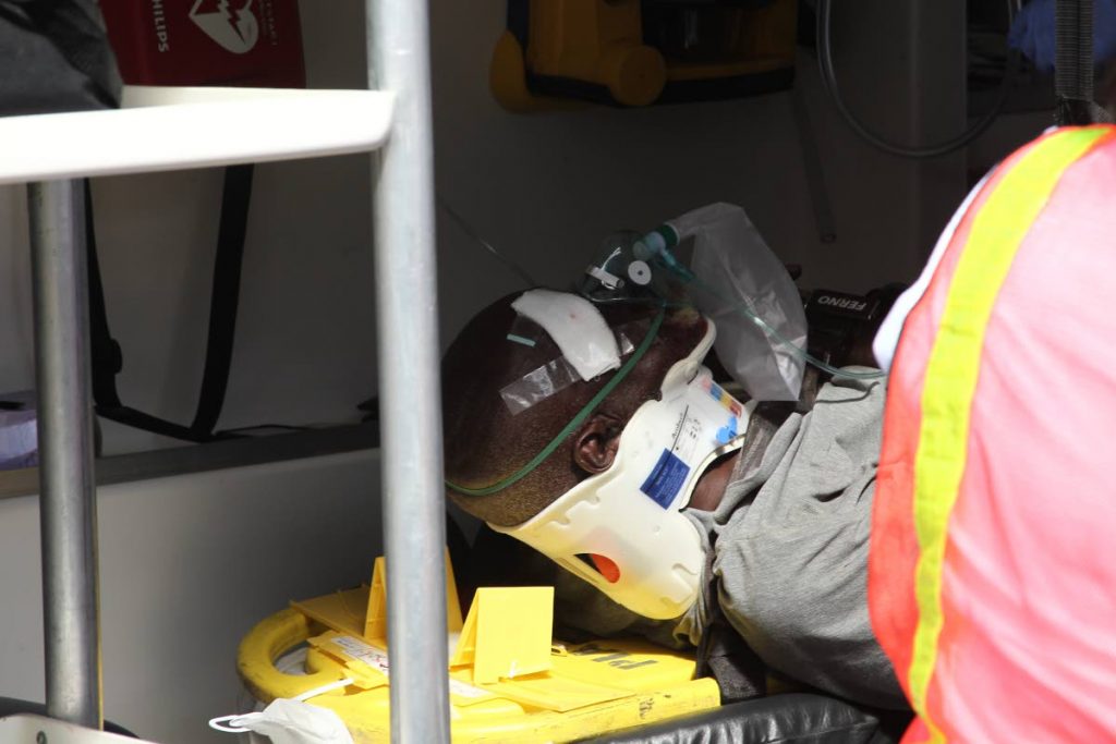 Emergency response technicians treat Albert Alexander who had been rescused after being pinned under a van on Lower Hillside Street, San Fernando, yesterday.