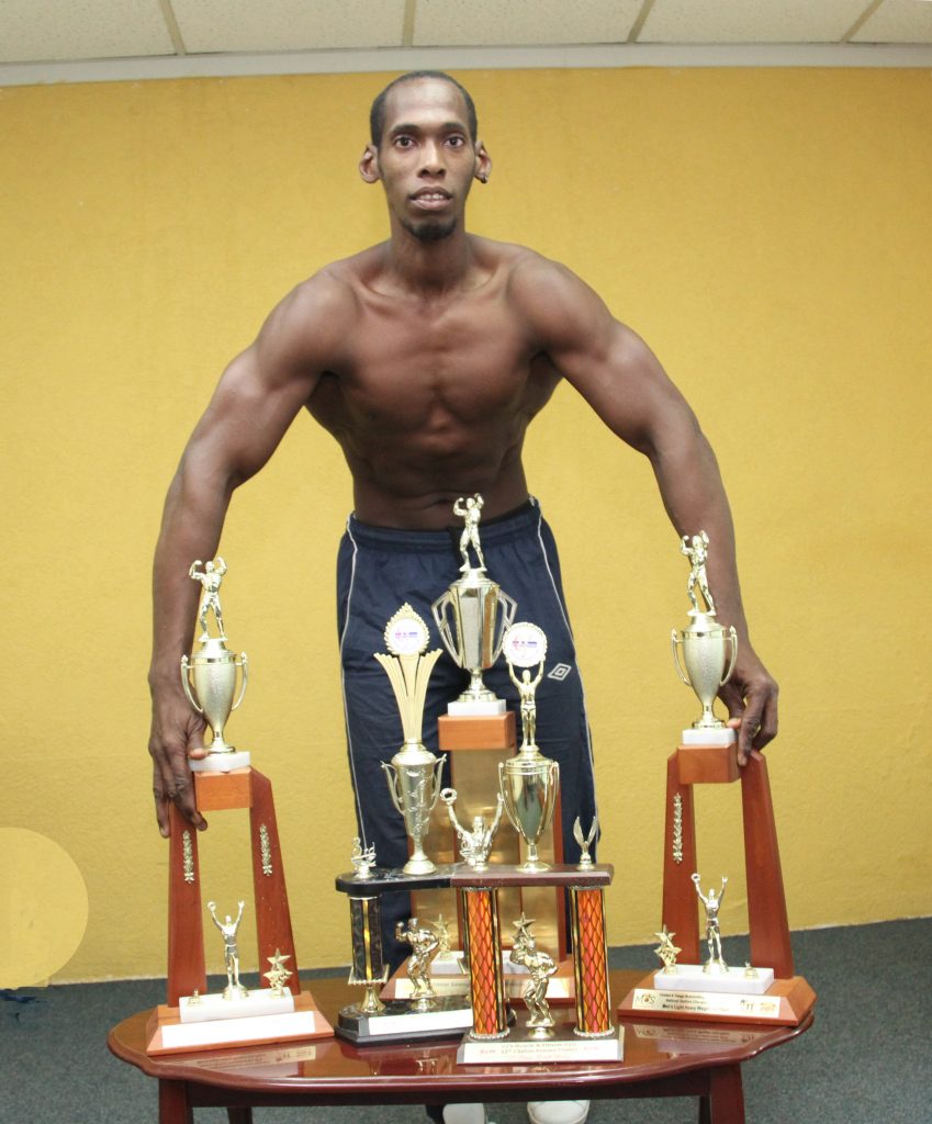 Body-builder Evan Jackson poses with trophies he has won over the years competing in the TT 
body-building circuit. PHOTO BY SUREASH CHOLAI