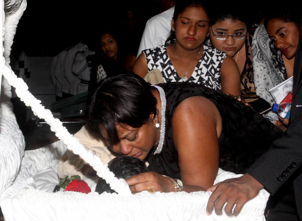STILL GRIEVING: Asha Boodooram, wife of slain prison officer Devendra Boodooram, weeps over his body during his funeral at the Faith Assembly International Church, Arouca on February 1. PHOTO BY ANGELO MARCELLE
