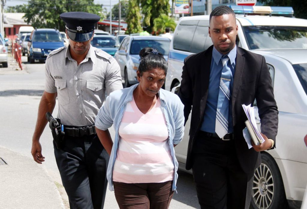 TO COURT: Susan Ramjattan is escorted into the Chaguanas Magistrates’ Court yesterday to answer a charge of fraud.