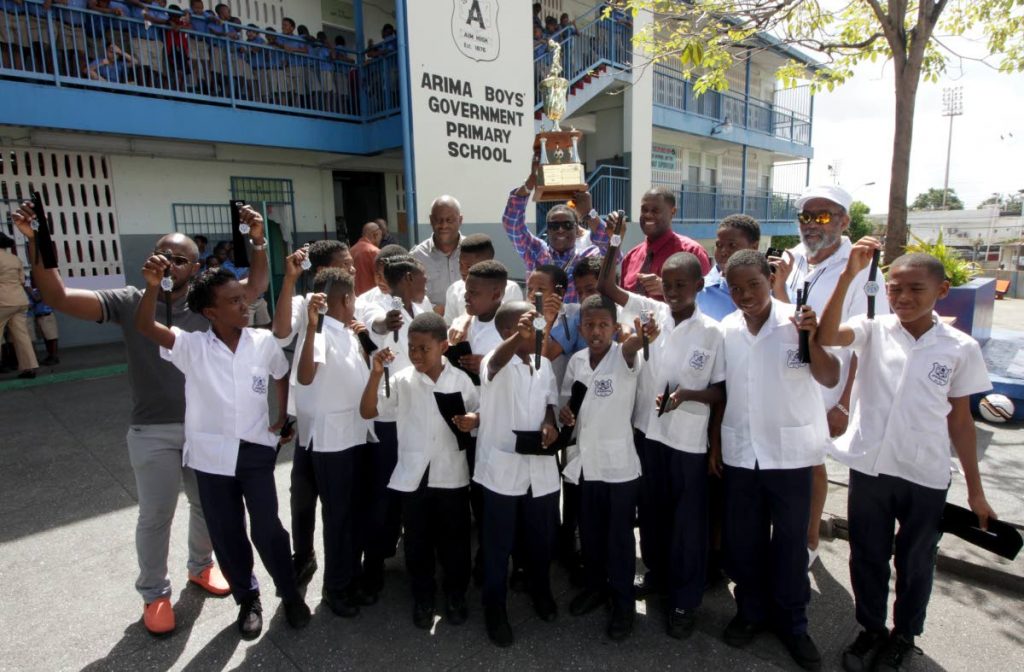 Ainsley Armstrong, back centre, holds up the Atlantic National Primary Schools Football trophy as members of the victorious Arima Boys Government team, coach and principal pose at the school compound at King Street, Arima.