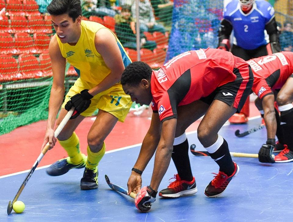 Trinidad and Tobago’s Kristien Emmanuel (centre) tries to get the ball from Australia’s Jake Sherren (left) during yesterday’s match in the FIH Indoor Hockey World Cup in Berlin, Germany. Also in photo are TT’s captain Solomon Eccles (right) and goalkeeper Ron Alexander. PHOTO COURTESY FIH.