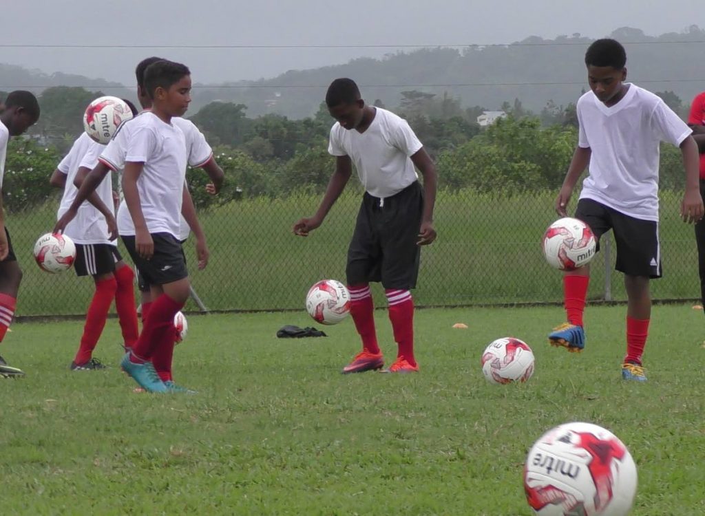 Youths juggle the football during a recent Under-14 boys football session hosted by the TTFA and NLCB.