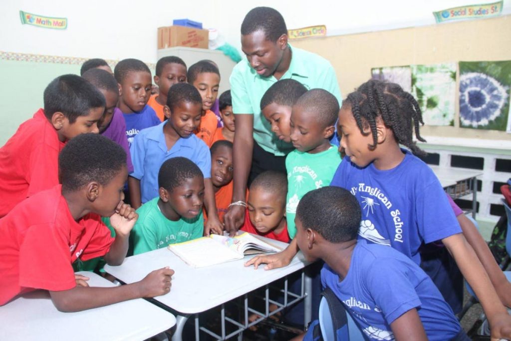 A good teacher: Standard two students surround their teacher Adriel Benjamin as they do storytelling 
at St Paul’s Anglican School, San Fernando. Photo by Ansel Jebodh