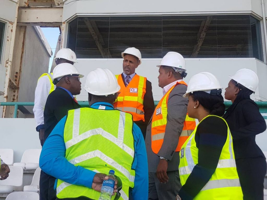 Sports Minister Darryl Smith, third from right, chats with THA Secretary of Sport Jomo Pitt, back centre, Tourism Minister Shamfa Cudjoe, second from right, and other stakeholders on a tour of the Dwight Yorke Stadium in Bacolet yesterday.